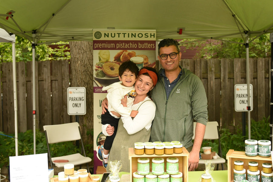 Family standing at a Nuttinosh pistachio butter booth at an outdoor market