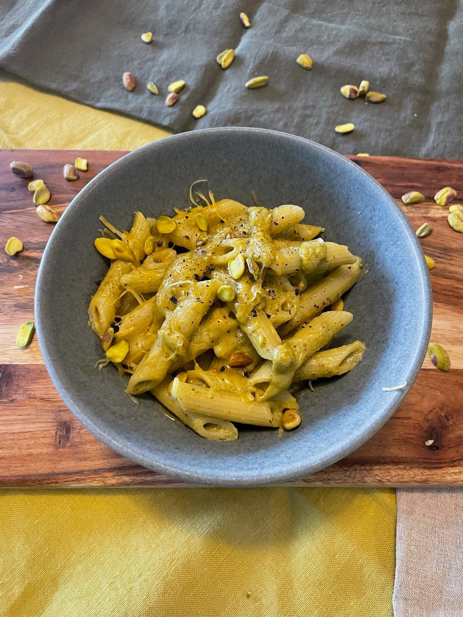Penne pasta tossed in creamy pistachio sauce served in a bowl with chopped pistachios