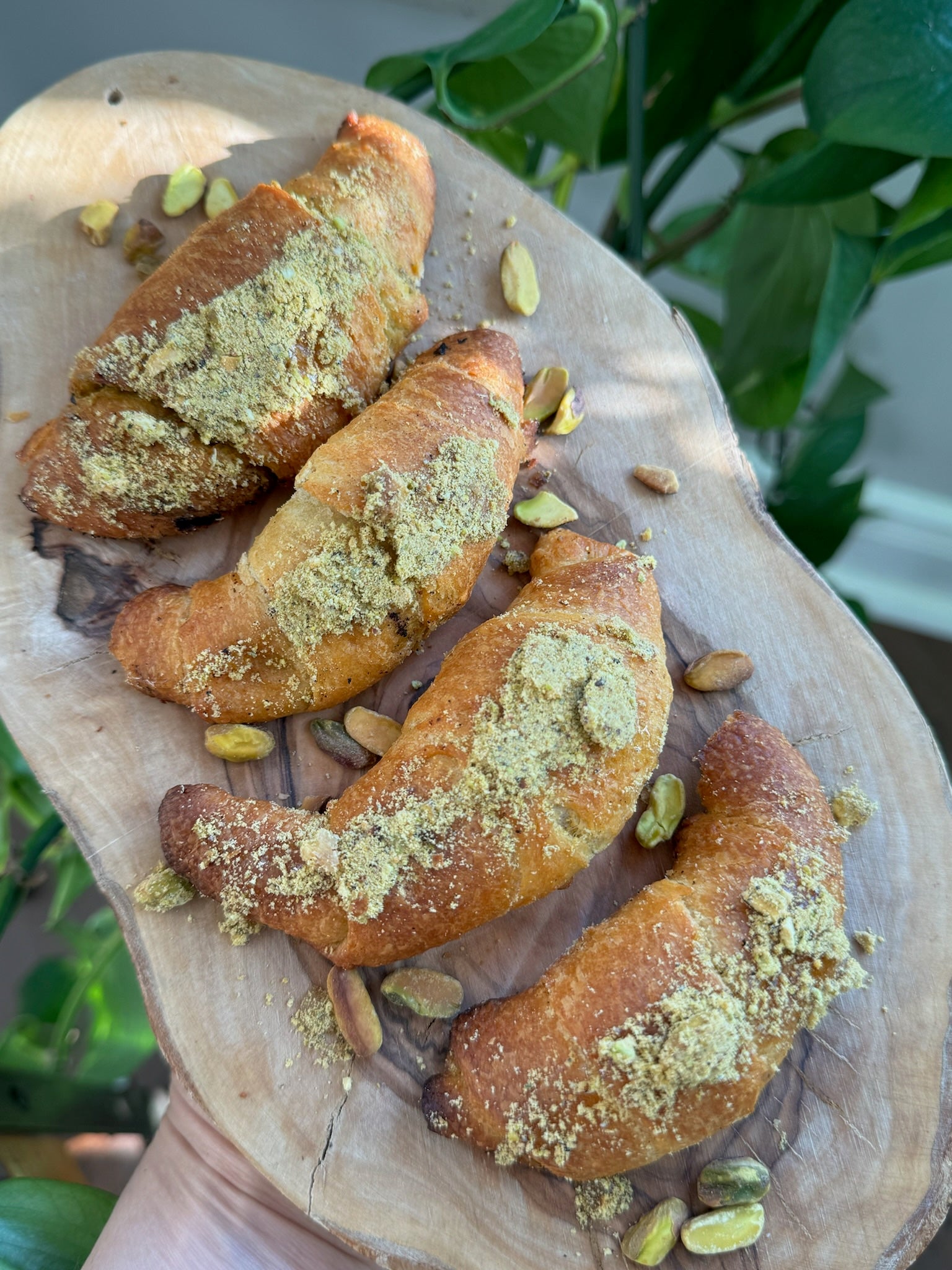 Pistachio butter-filled croissants arranged neatly on a walnut cutting board.