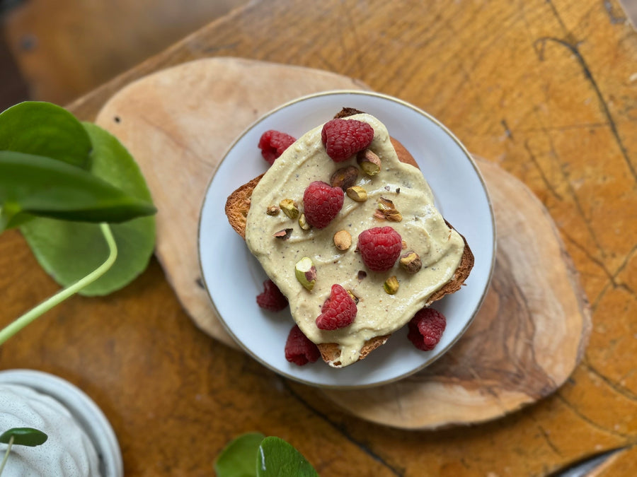French toast with pistachio butter spread, fresh raspberries and crushed pistachios garnished on top