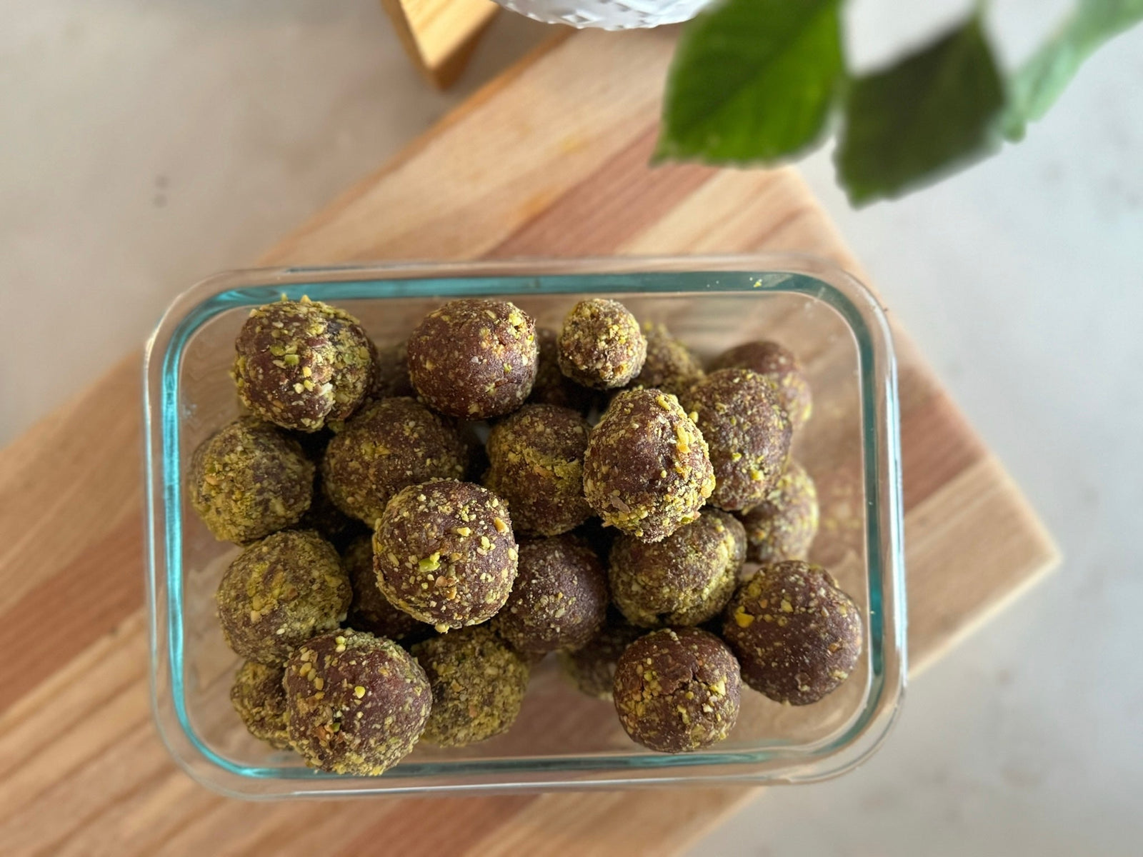 Chocolate pistachio energy snacks topped with crushed pistachios in a glass container
