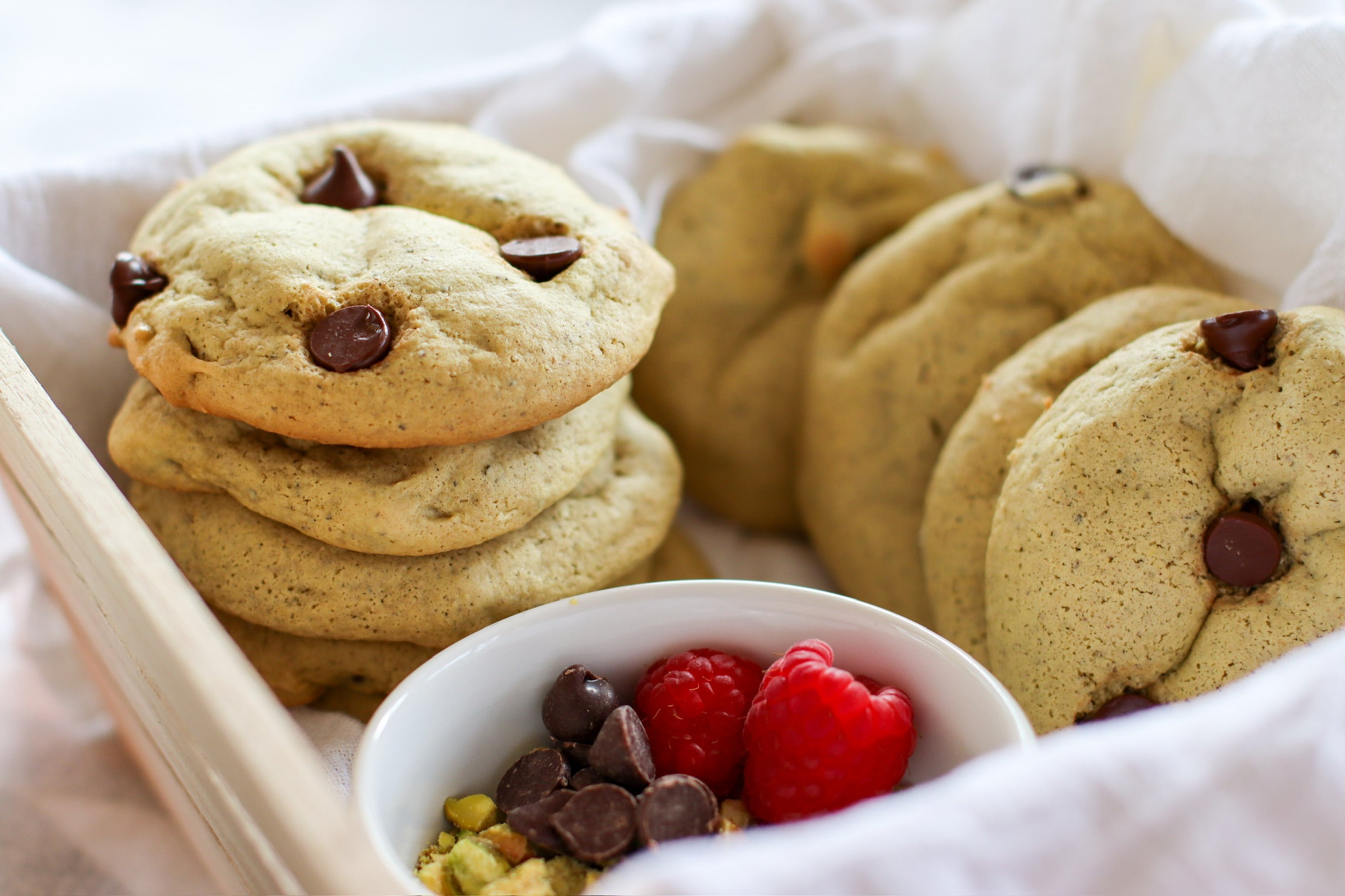 Pistachio butter chocolate chip cookies are neatly stacked in a square dish.