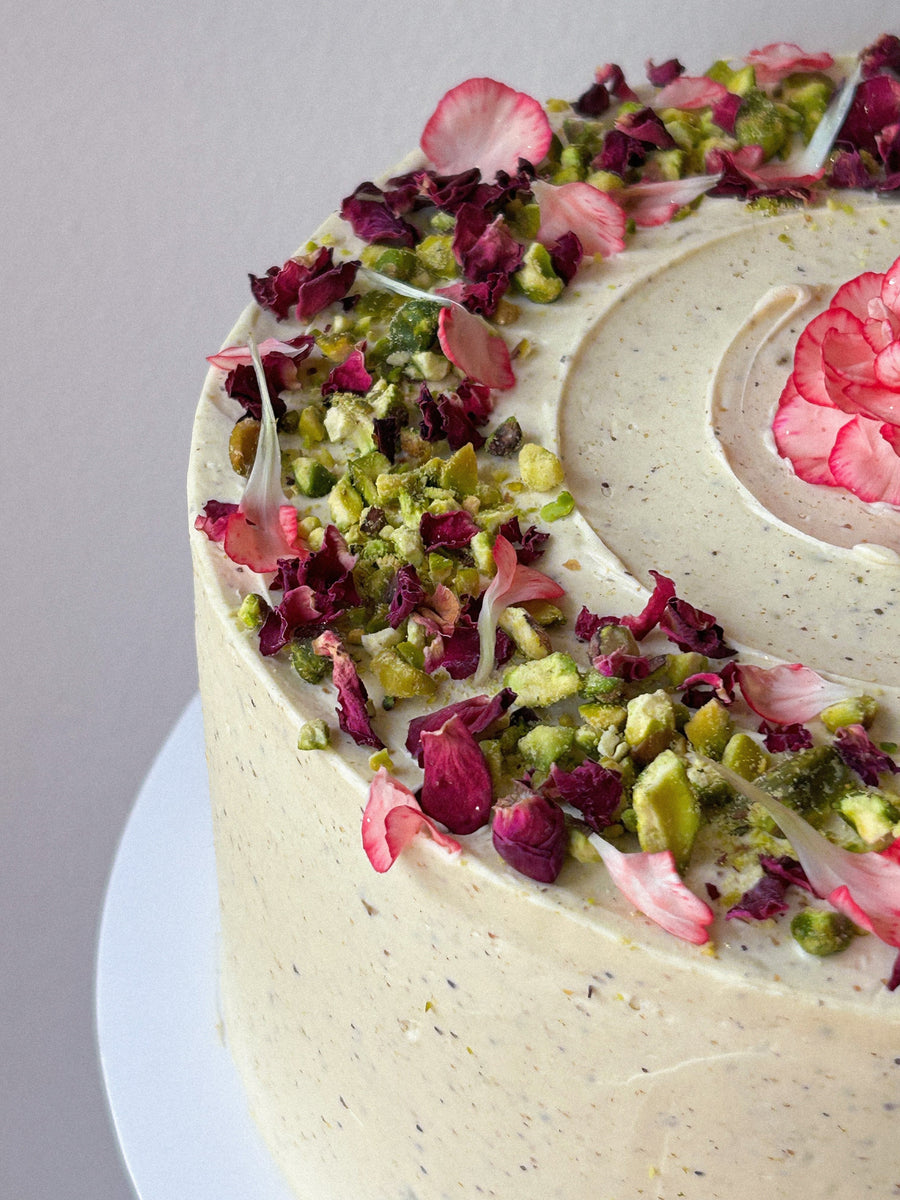 Pistachio cake decorated with crushed pistachios and edible flower petals