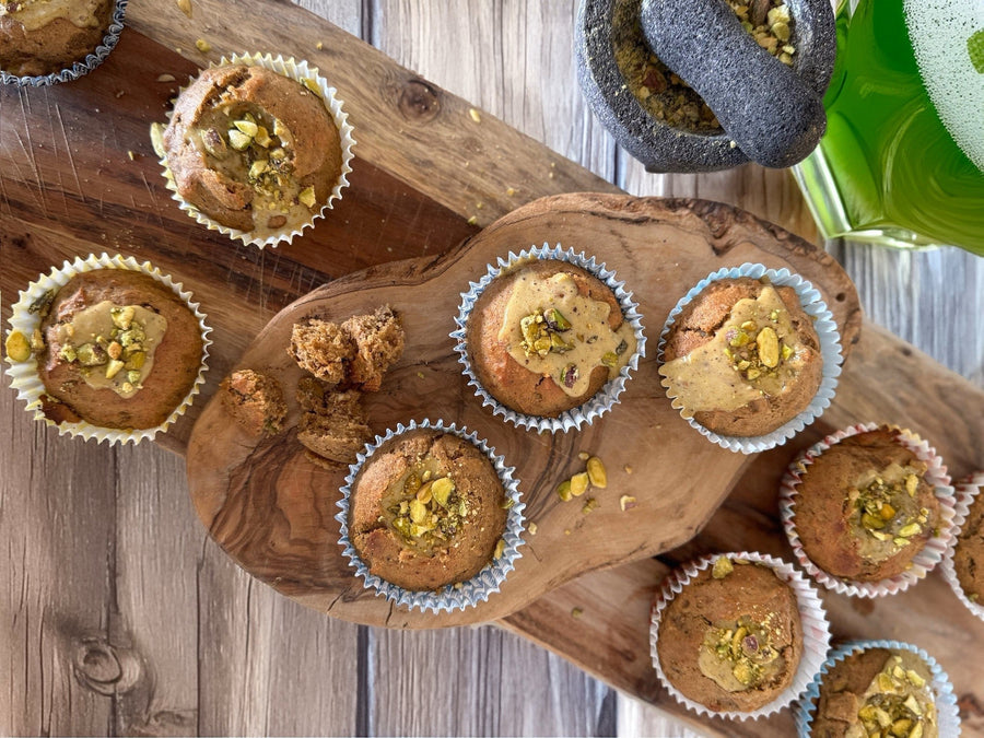 Pistachio muffins topped with chopped pistachios arranged on a wooden board