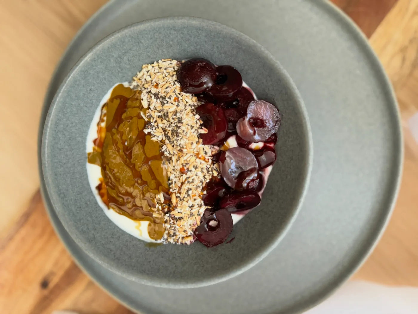 Cherry pistachio yogurt bowl topped with cherries, granola, and honey