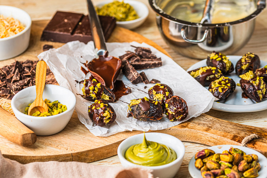 Chocolate pistachio truffles topped with chopped pistachios on a wooden board with pistachio butter and chocolate ingredients