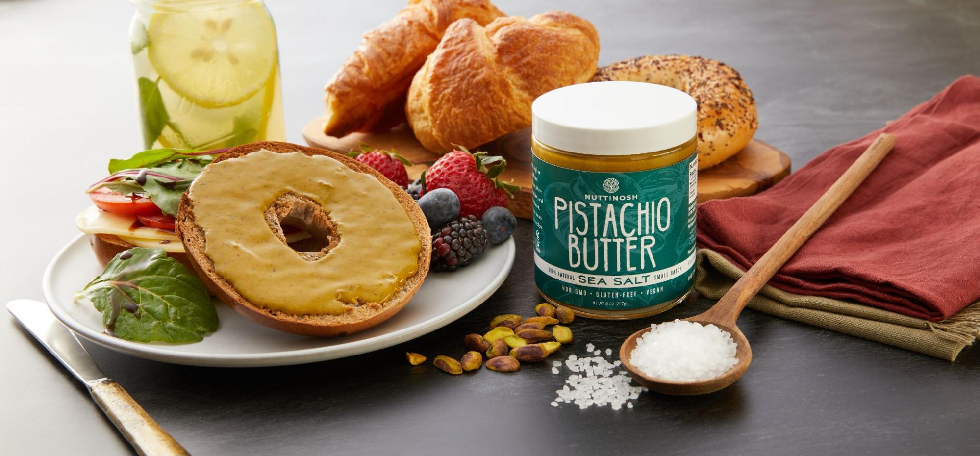 Nuttinosh pistachio butter jar served with bagel, fruit, croissant, and breakfast ingredients