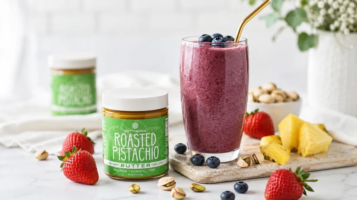 Nuttinosh roasted pistachio butter jars with strawberries, pistachios, and a berry smoothie on a table