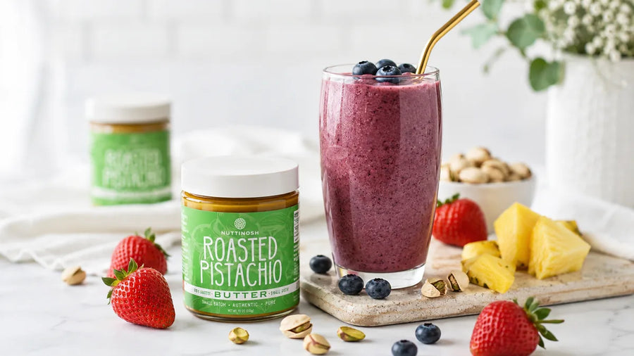 Nuttinosh roasted pistachio butter jars with strawberries, pistachios, and a berry smoothie on a table