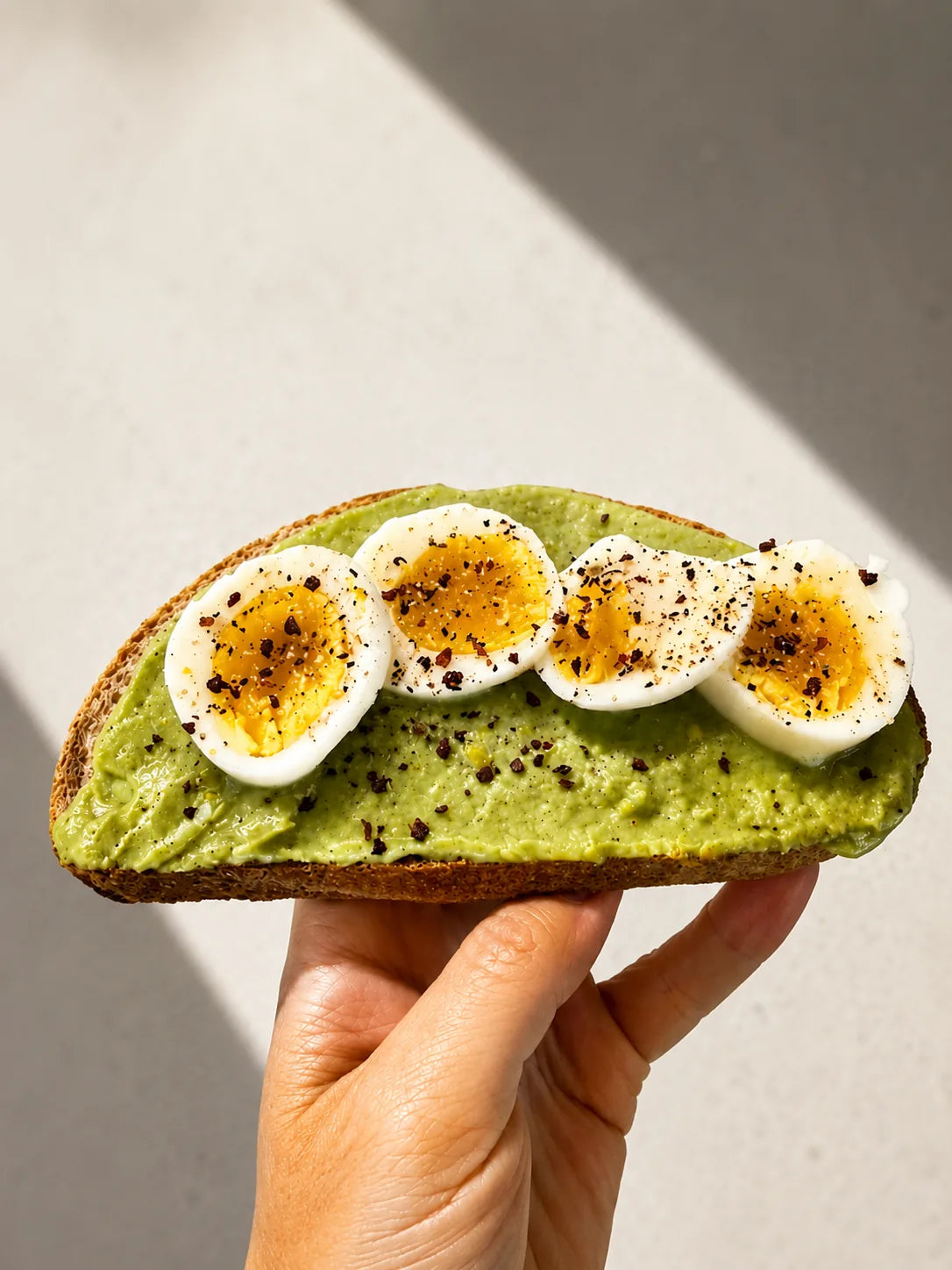 Toast topped with creamy pistachio spinach spread and sliced soft-boiled eggs