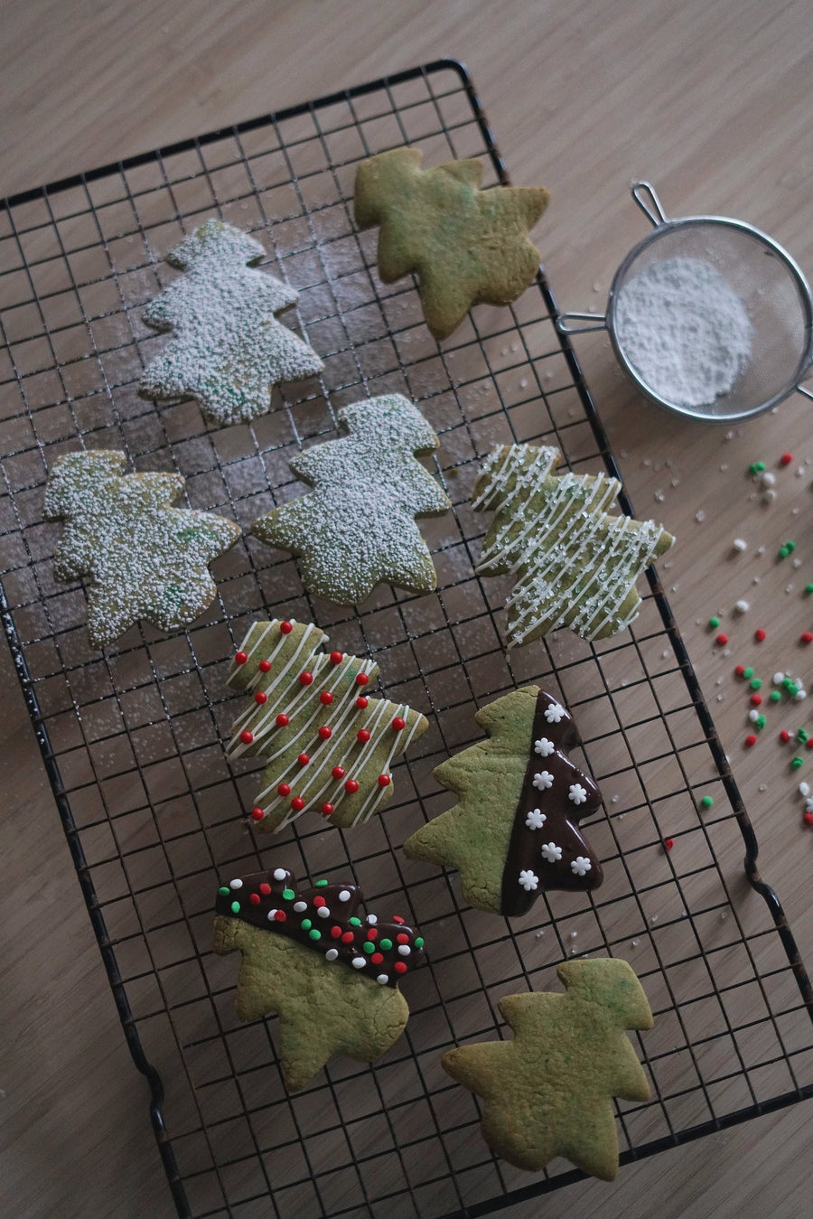 Christmas tree–shaped cookies decorated with icing and sprinkles on a cooling rack