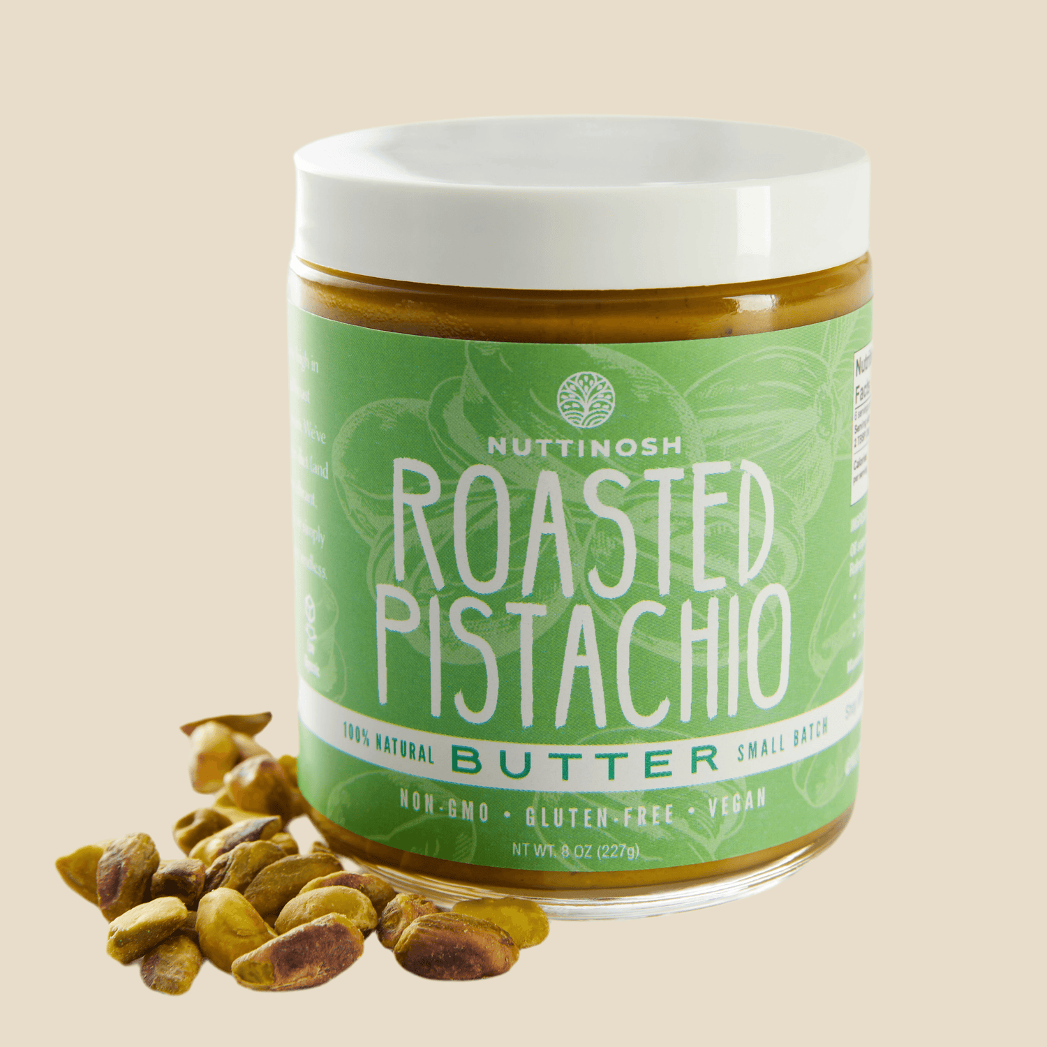 Jar of Nuttinosh roasted pistachio butter with green label and white lid, placed next to pistachios.